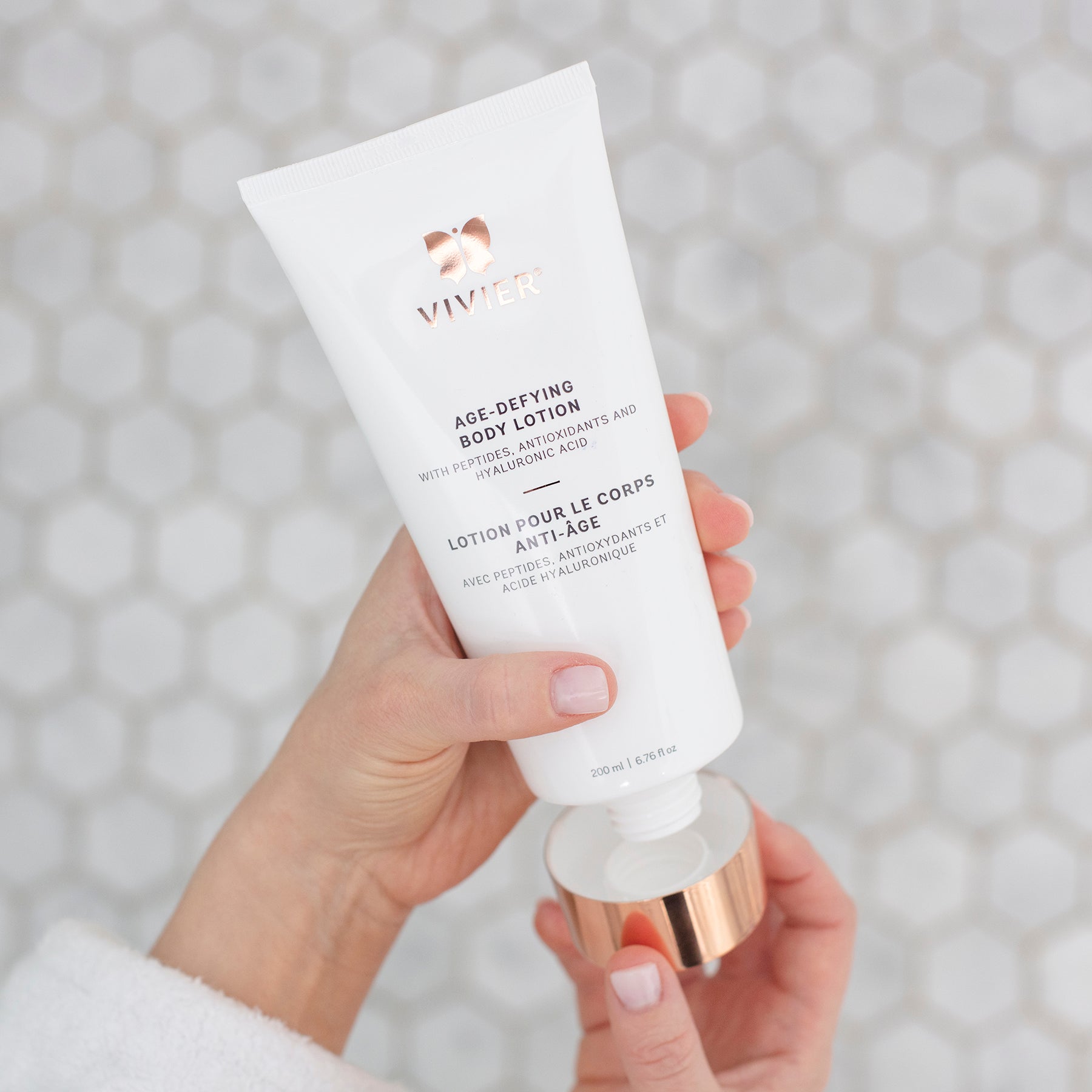 Vivier Age-Defying Body Lotion in hand, featuring peptides and antioxidants for firm and hydrated skin.