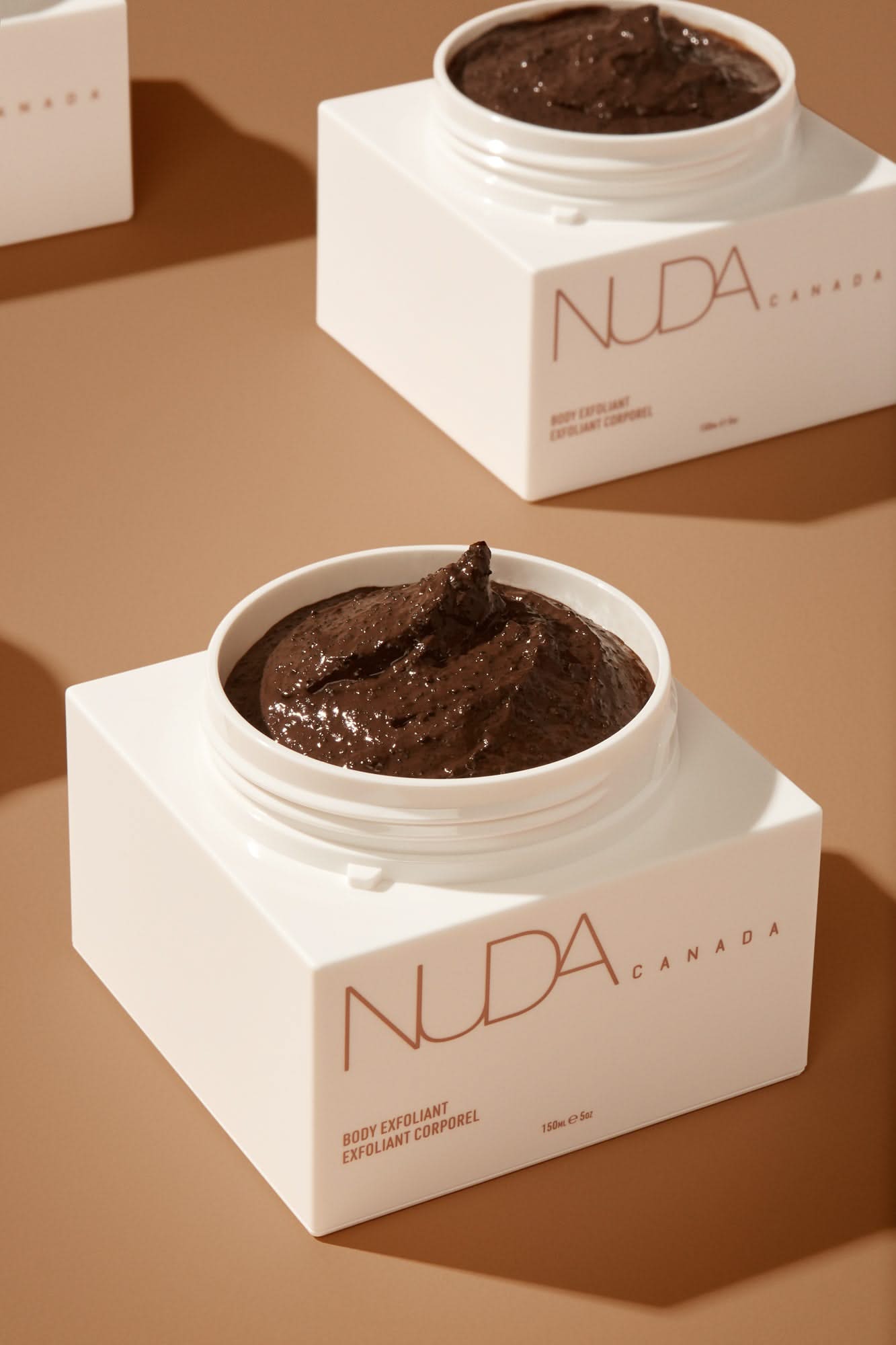 Nuda Canada Body Exfoliant in a sleek white jar, featuring a rich, textured formula for radiant skin.