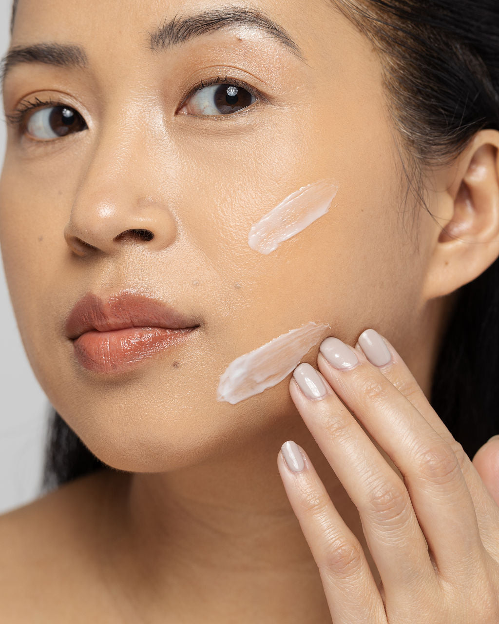 Woman applying Vivier Exfoliant Forte lotion on her face to enhance skin texture and brightness.