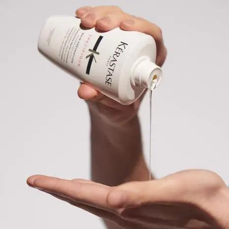 Pouring Kerastase hair product onto hand for hair treatment.