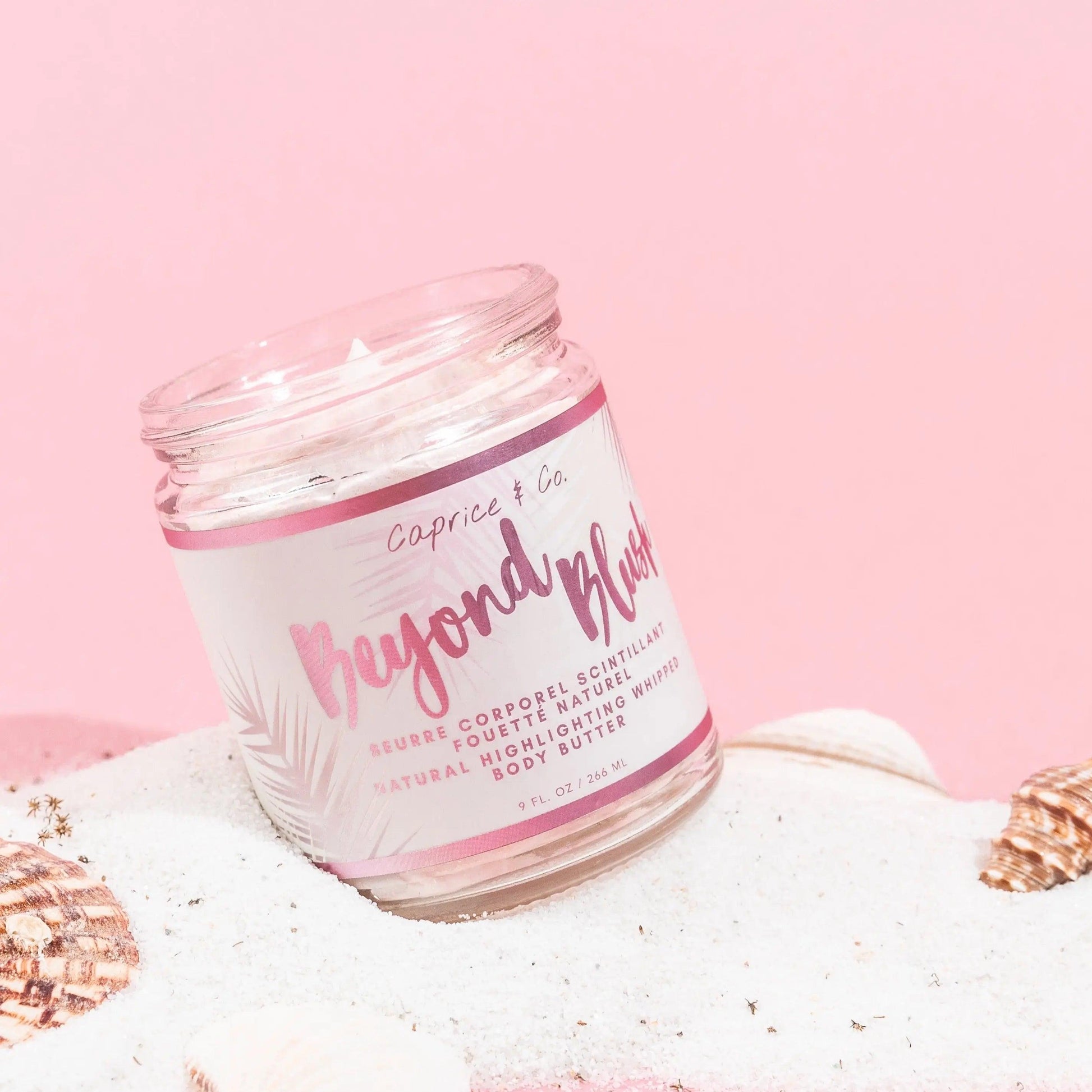 Beyond Blush Highlighting Body Butter in a jar on sand, showcasing natural whipped texture and tropical vibe.