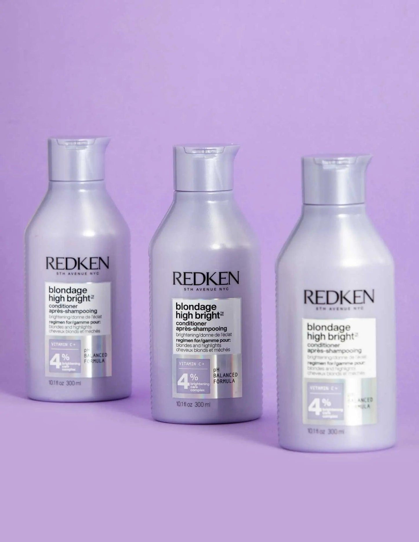 Redken Blondage High Bright Conditioner bottles for vibrant blonde hair care on a lavender background.