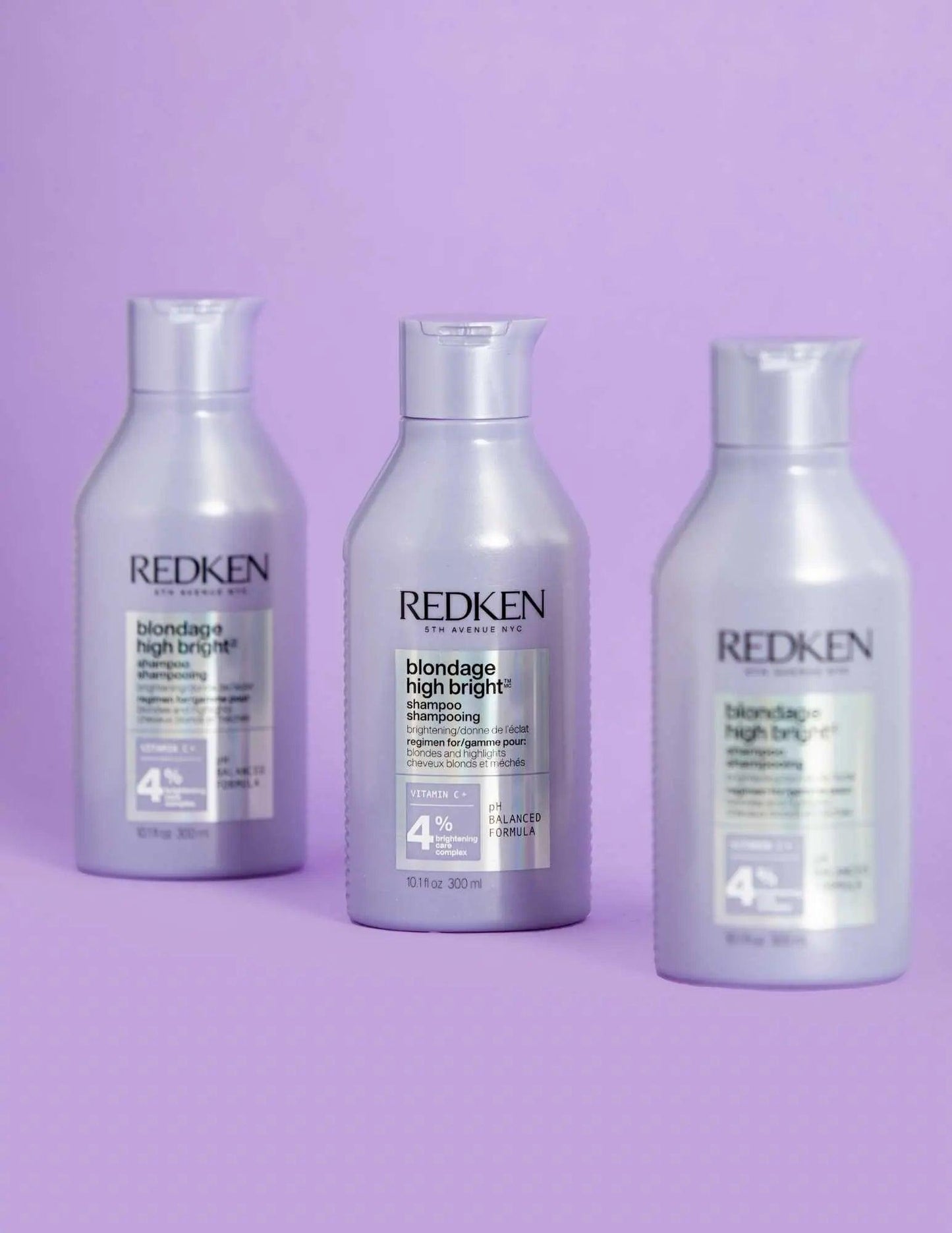 Three bottles of Redken Blondage High Bright Shampoo against a purple background, ideal for vibrant blonde hair.
