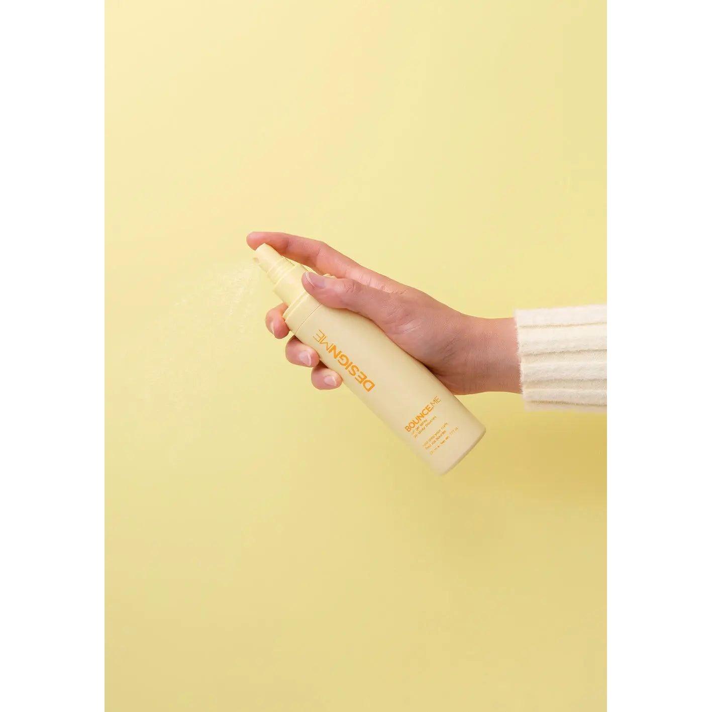 Hand holding yellow hair product bottle against yellow background