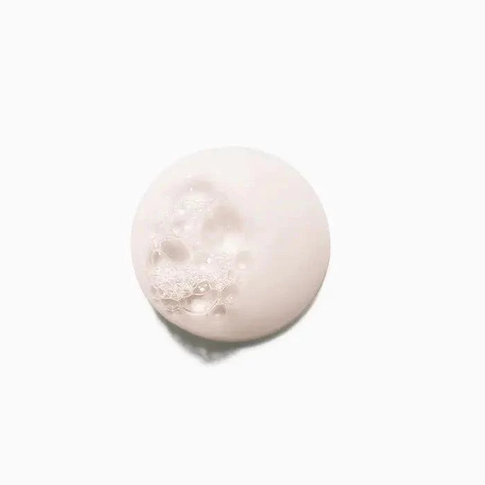 White round soap with lather bubbles on a minimal white background