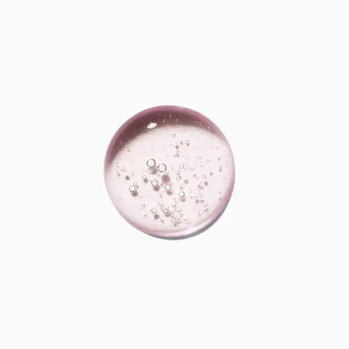 Clear pink serum drop with visible air bubbles on white background