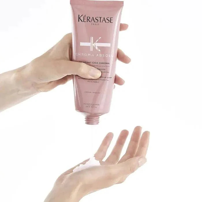 Kerastase Paris hair care product being dispensed into hand for hair treatment.