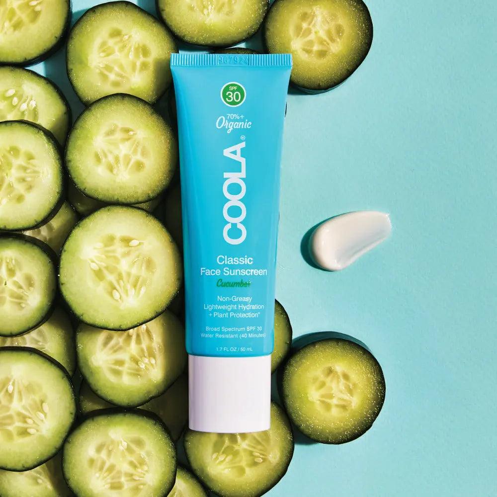 Coola Classic Face Organic Sunscreen Lotion SPF 30 with cucumber slices on a vibrant blue background, showcasing its hydrating formula.
