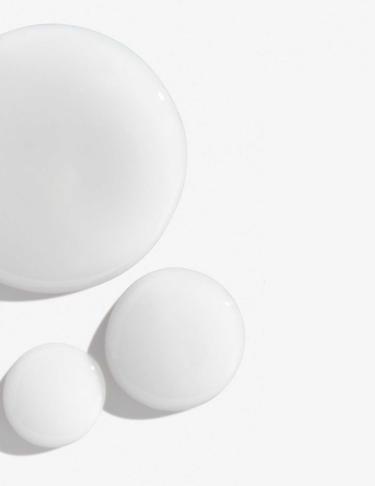 Drops of creamy white shampoo on a smooth surface, ideal for color-treated hair care.