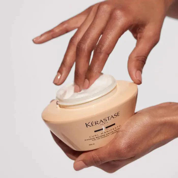 Hands applying Curl Manifesto Masque Beurre Haute Nutrition hair mask for nourishing curly hair.