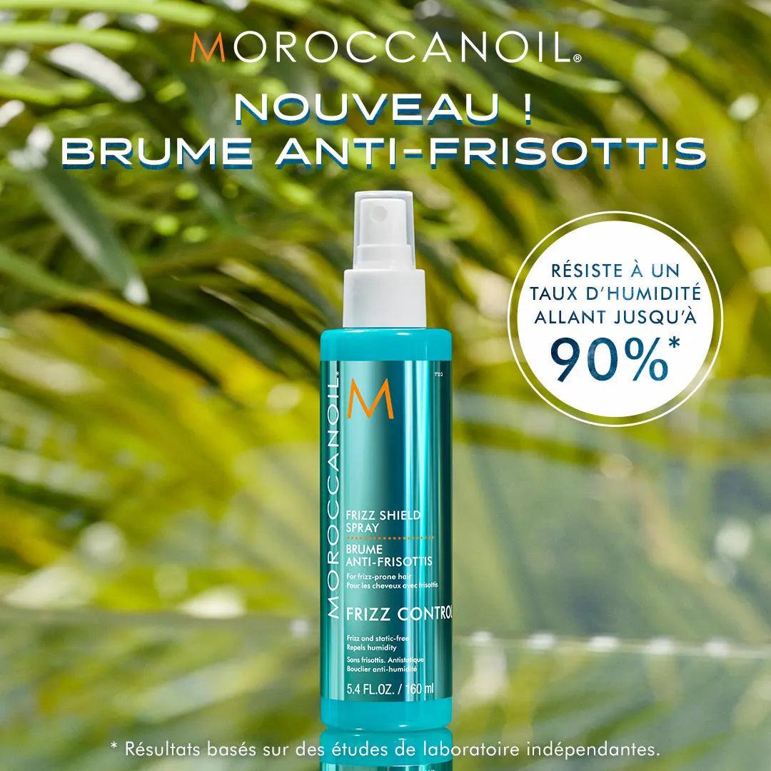 Moroccanoil Frizz Shield Spray bottle on a tropical background, showcasing humidity resistance and frizz control benefits.