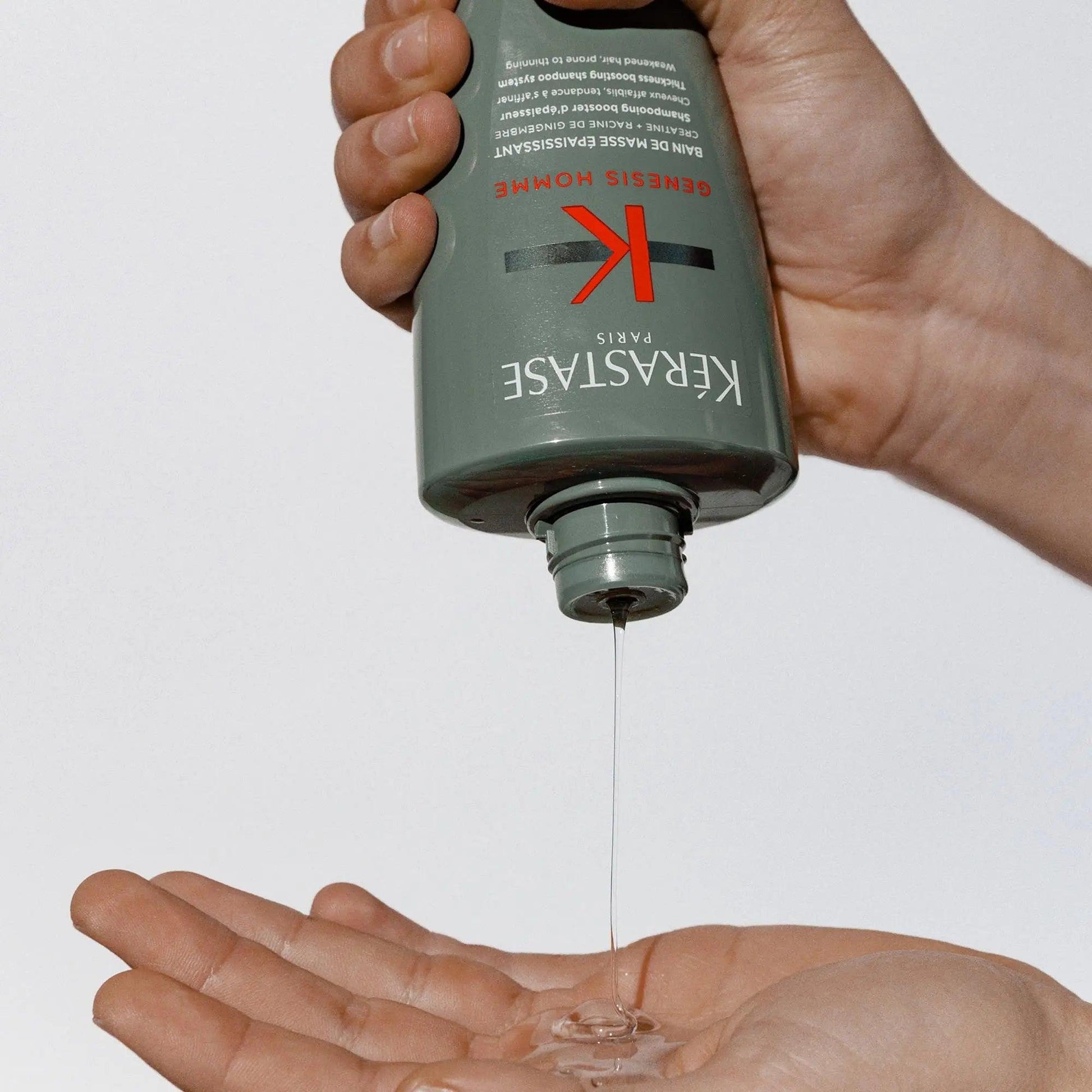 Kérastase Genesis Homme Bain De Masse Épaississant Shampoo pouring into hand, promoting thicker hair for men.