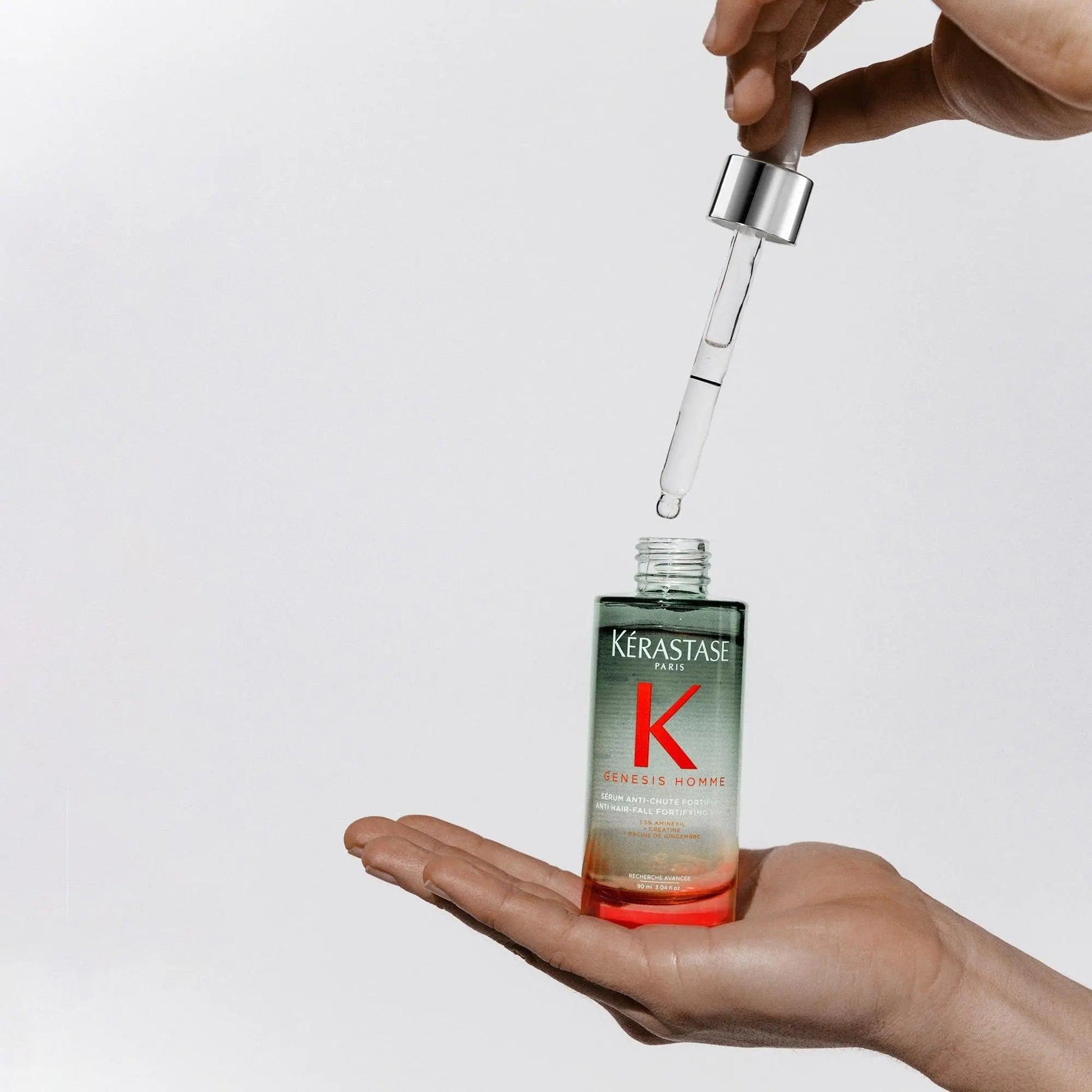 Kérastase Genesis Homme Sérum Anti-Chute Fortifiant being applied with a dropper, showcasing its hair loss treatment benefits.