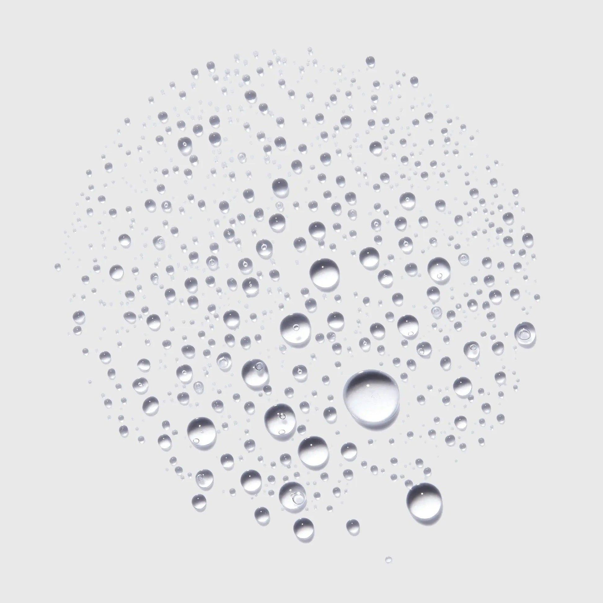 Close-up of water droplets forming a circular pattern on a light background, showcasing freshness and hydration.