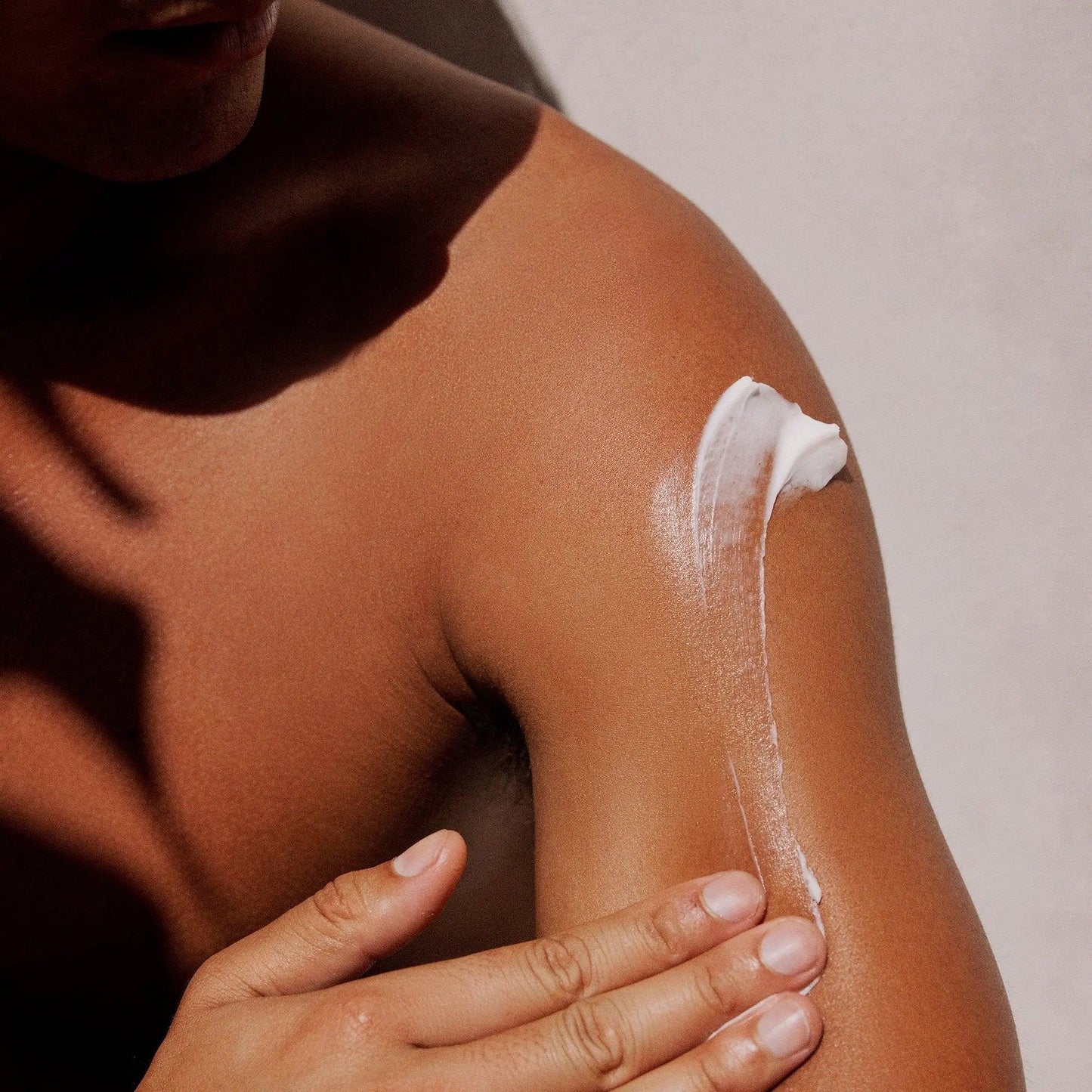 Close-up of a person applying Gilded Woods Body Lotion to their shoulder for hydration and nourishment.