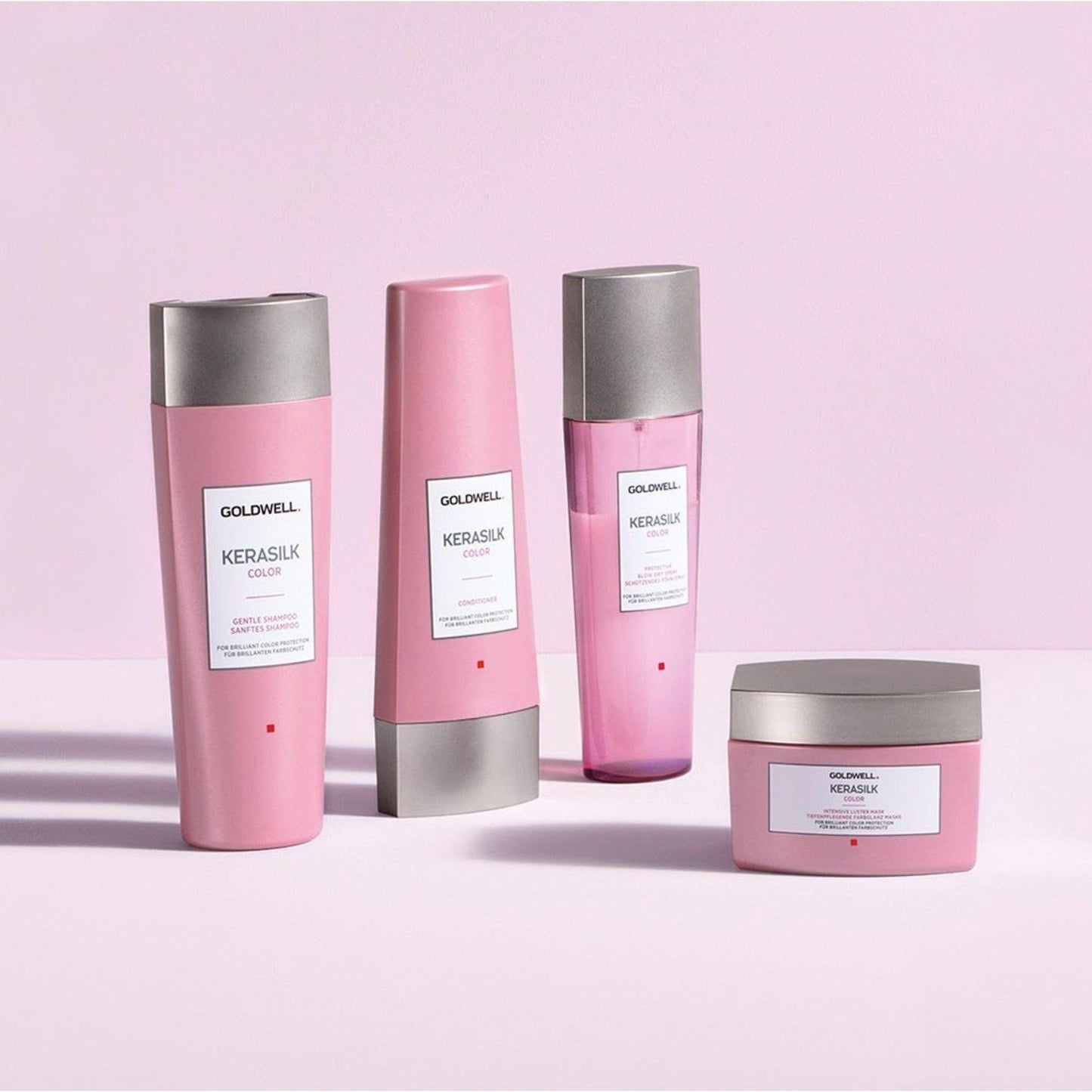 Goldwell Kerasilk Color products including intensive luster mask, treatment and shampoo on a pink background.