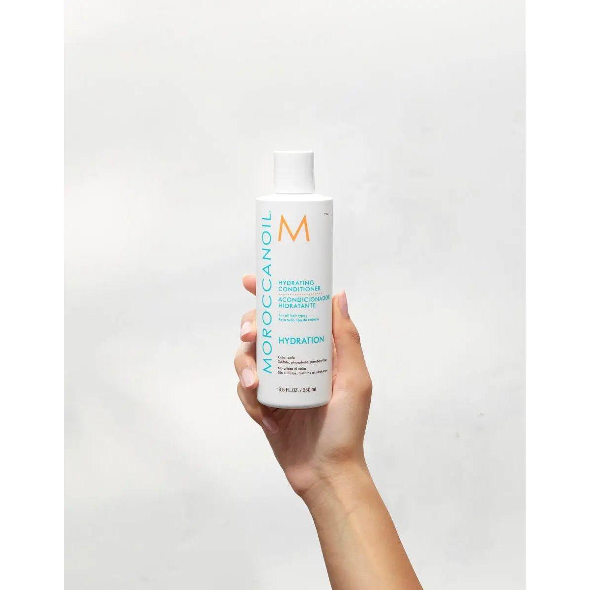 Moroccanoil Hydrating Conditioner bottle held in hand, perfect for detangling and moisturizing dehydrated hair.
