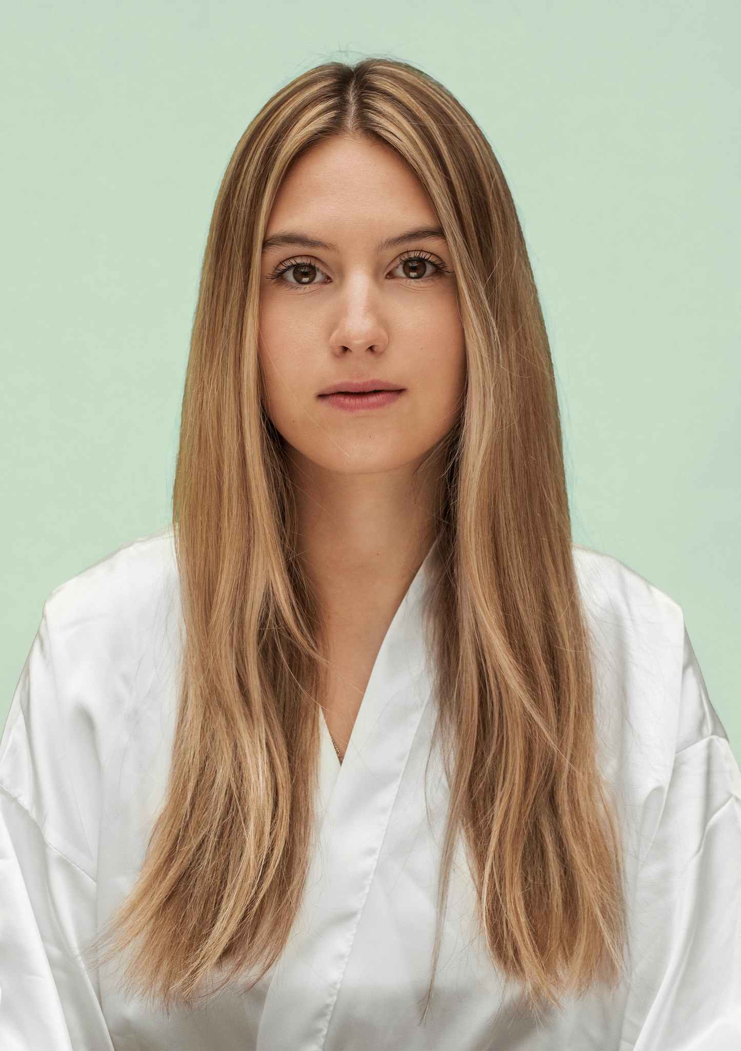 Woman with long, shiny hair wearing a white robe, showcasing healthy hair after using hydrating shampoo and conditioner.