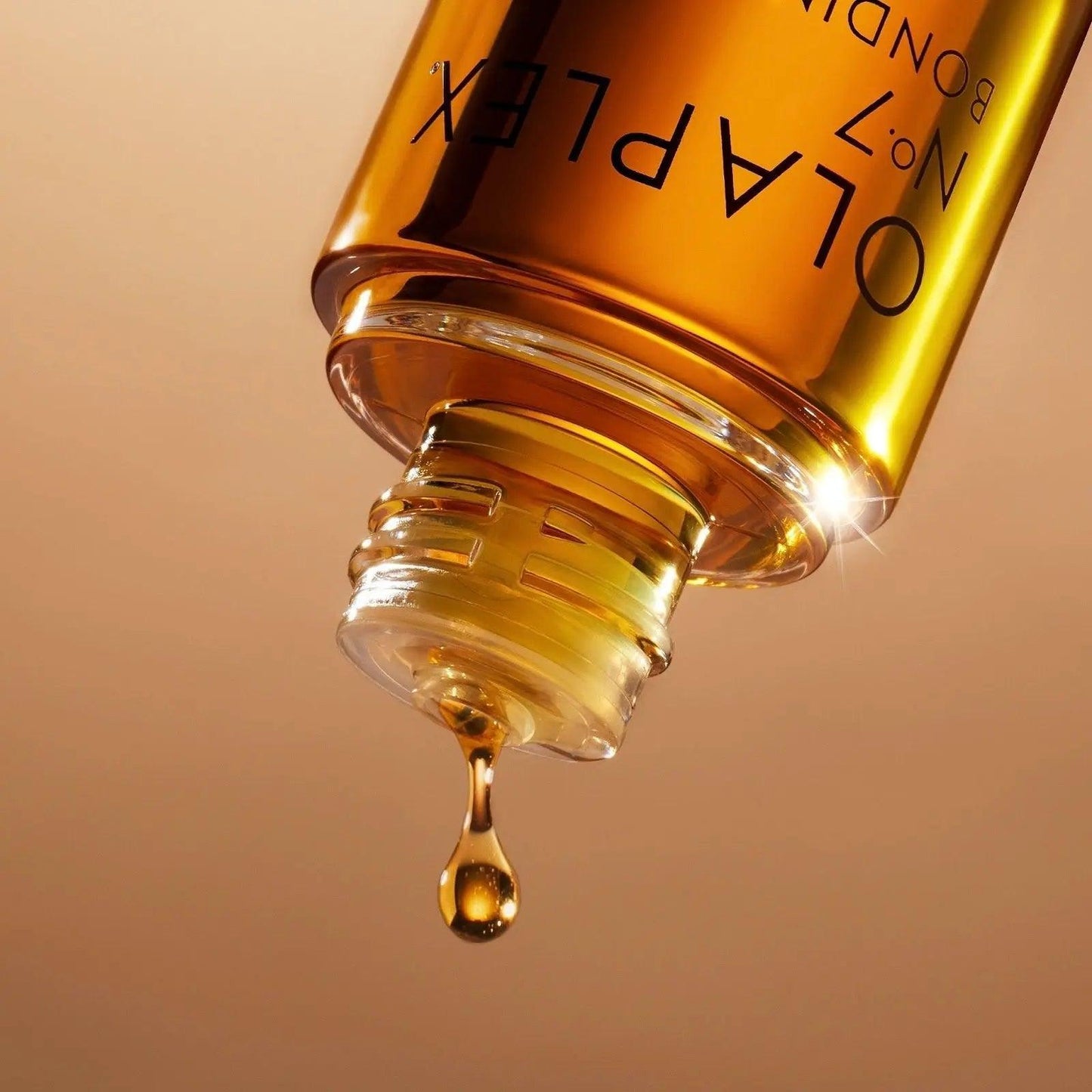 Close-up of Olaplex No.7 Styling Oil bottle, showcasing the golden oil dripping from the top for hair protection and shine.