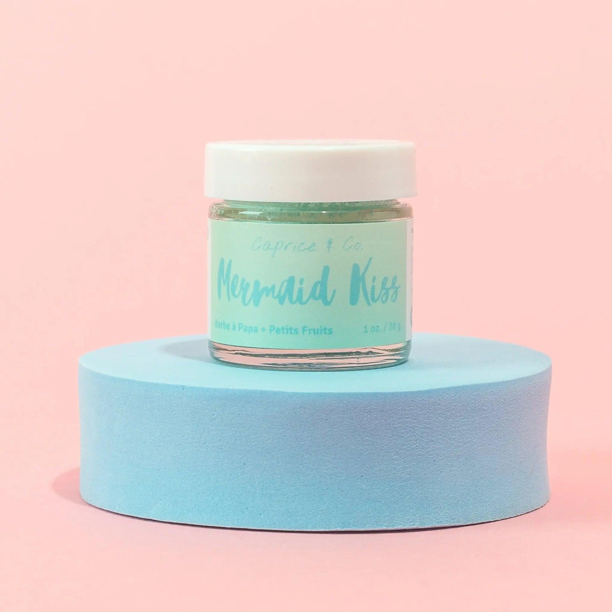 Mermaid Kiss lip scrub jar on a blue pedestal, featuring cotton candy and berries flavor, perfect for lip care.