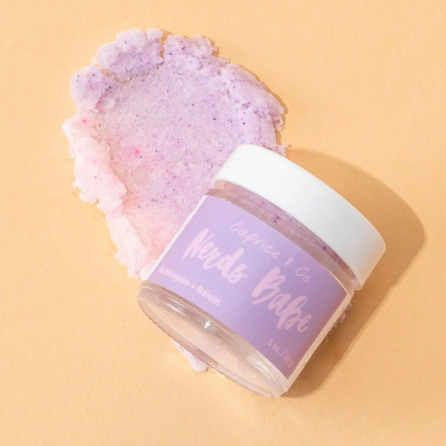 Nerds Babe lip scrub jar with bubblegum and grape flavor on a pastel background, showcasing vibrant purple hues.