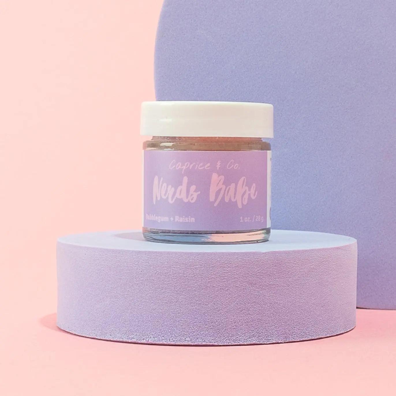 Nerds Babe lip scrub jar on a pastel backdrop, showcasing bubblegum and grape flavor, perfect for lip care routine.