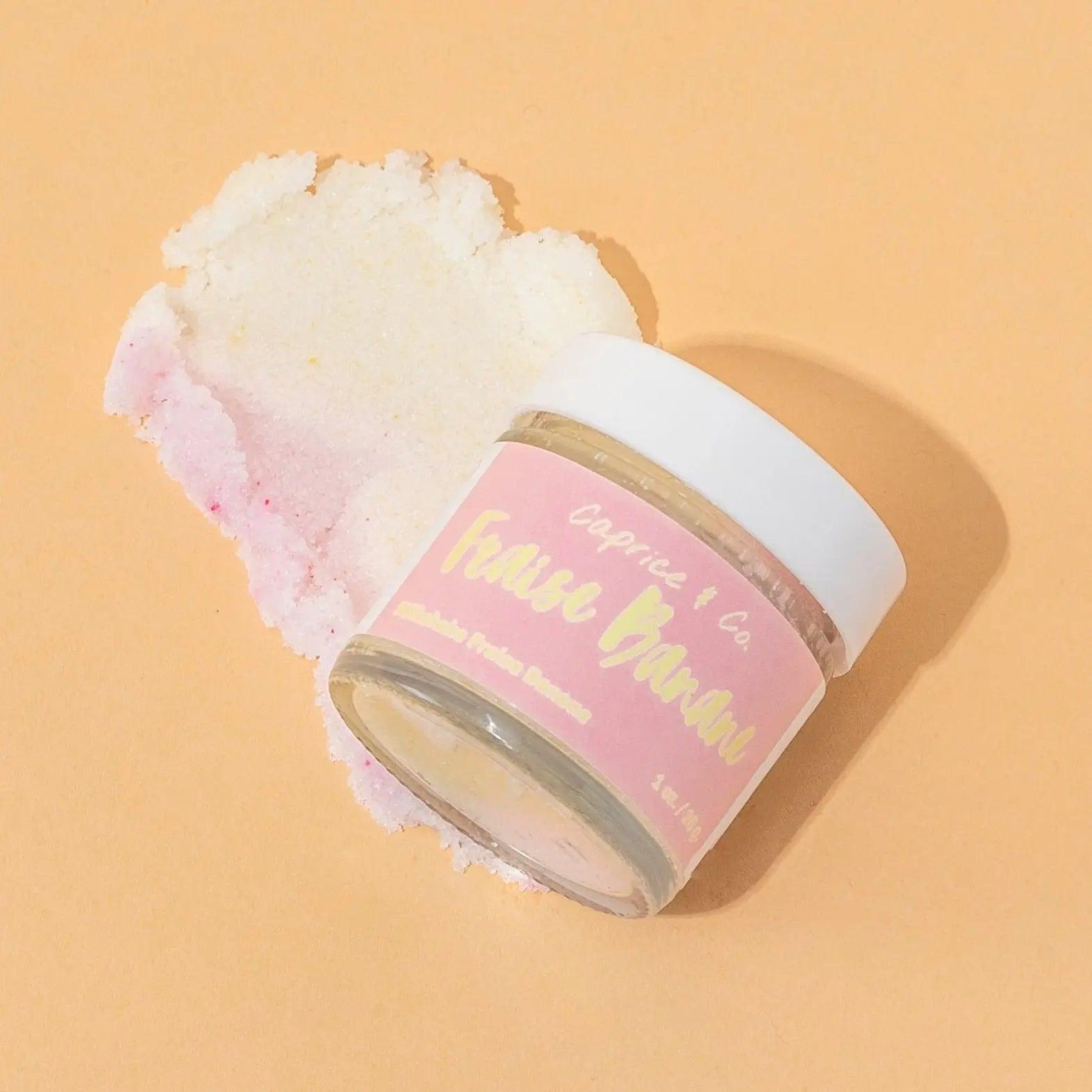 Strawberry banana lip scrub jar with exfoliating sugar scrub on a peach background. Perfect for smooth, soft lips.