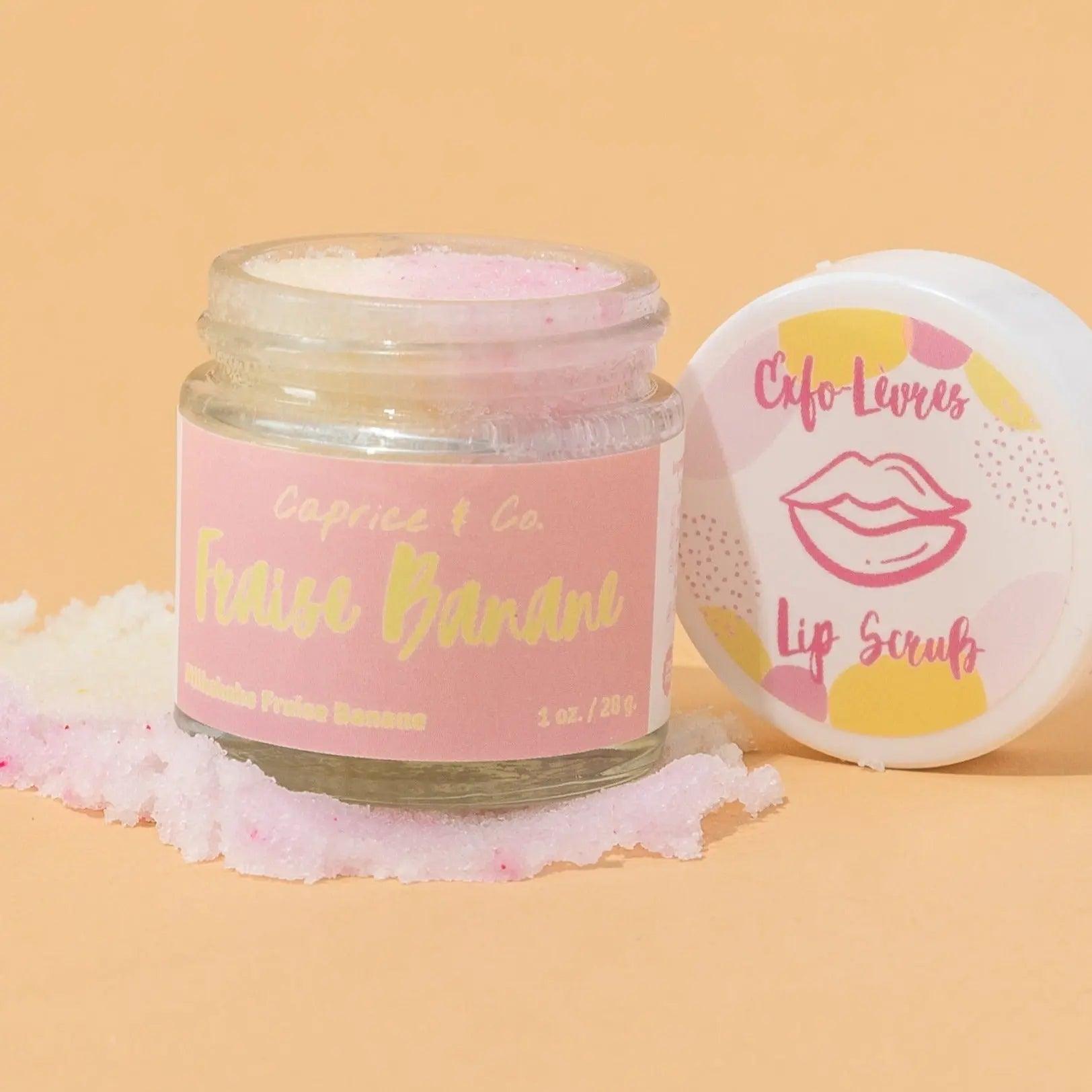 Strawberry banana lip scrub jar with pink label, featuring exfoliating sugar and natural ingredients, set against a pastel background.