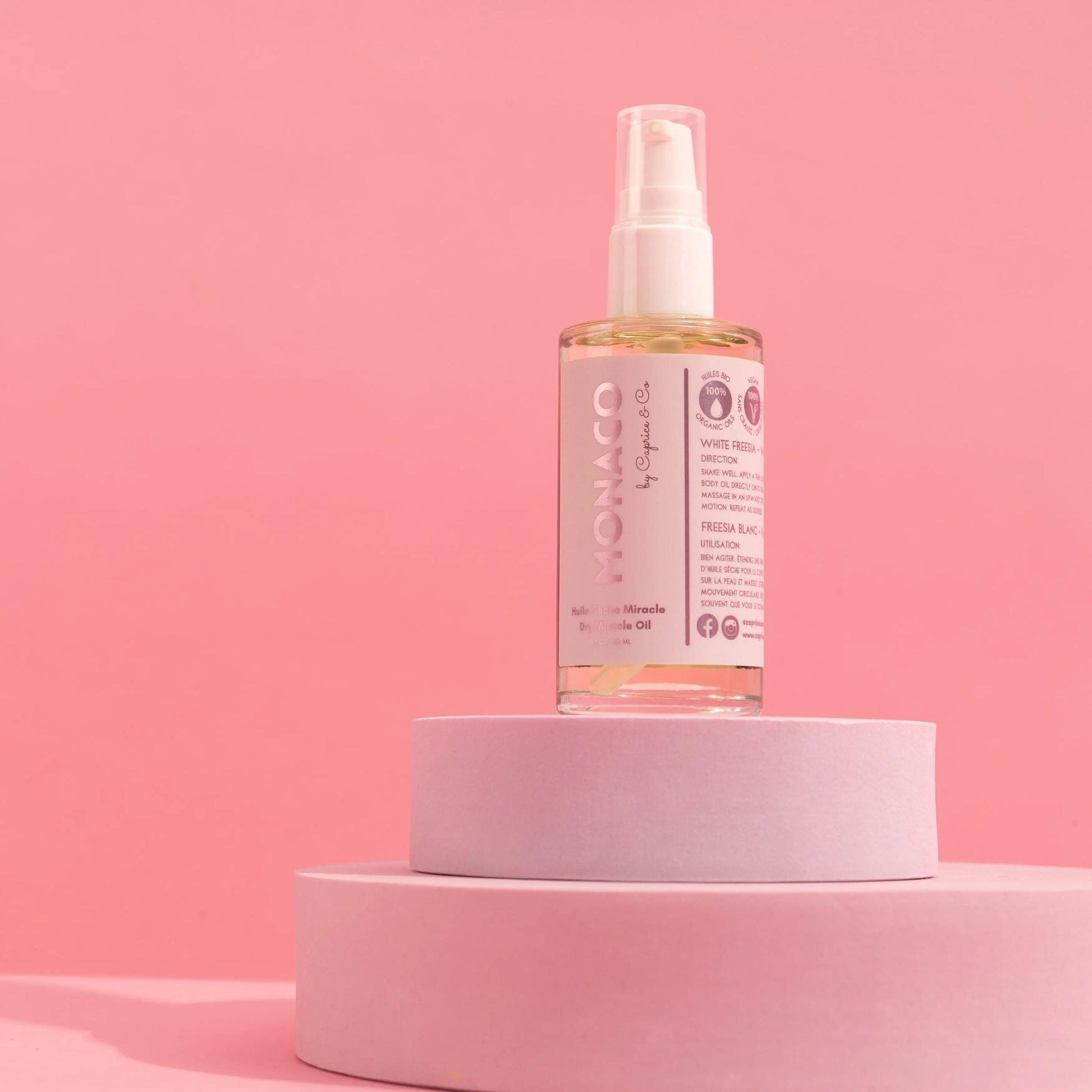 Monaco Dry Miracle Oil on pastel pink background, showcasing organic coconut oil and radiant glow for all skin tones.