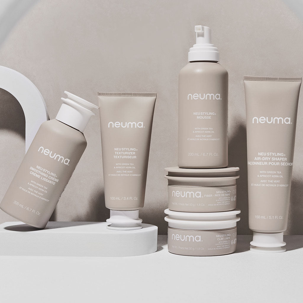 A collection of Neuma hair care products, including styling creams and shampoos, displayed elegantly on a neutral background.