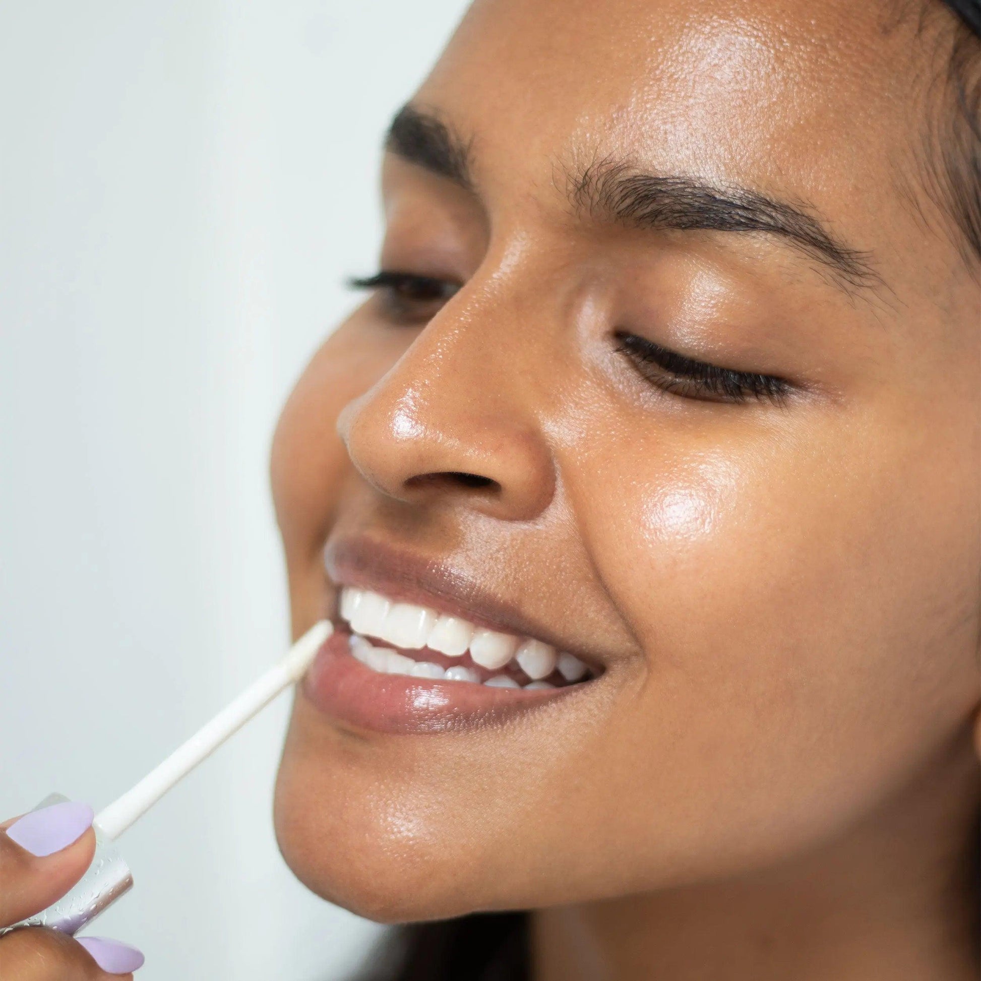 Model applying Night Lip Serum, showcasing hydrated lips and a radiant smile. Ideal for nighttime lip care.