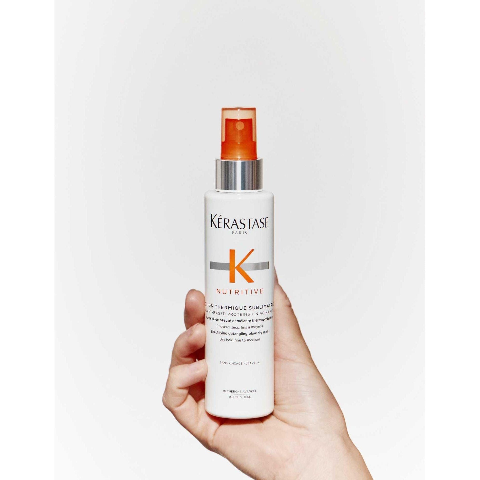 Kérastase Nutritive Lotion Thermique Sublimatrice spray for dry fine to medium hair in a hand.