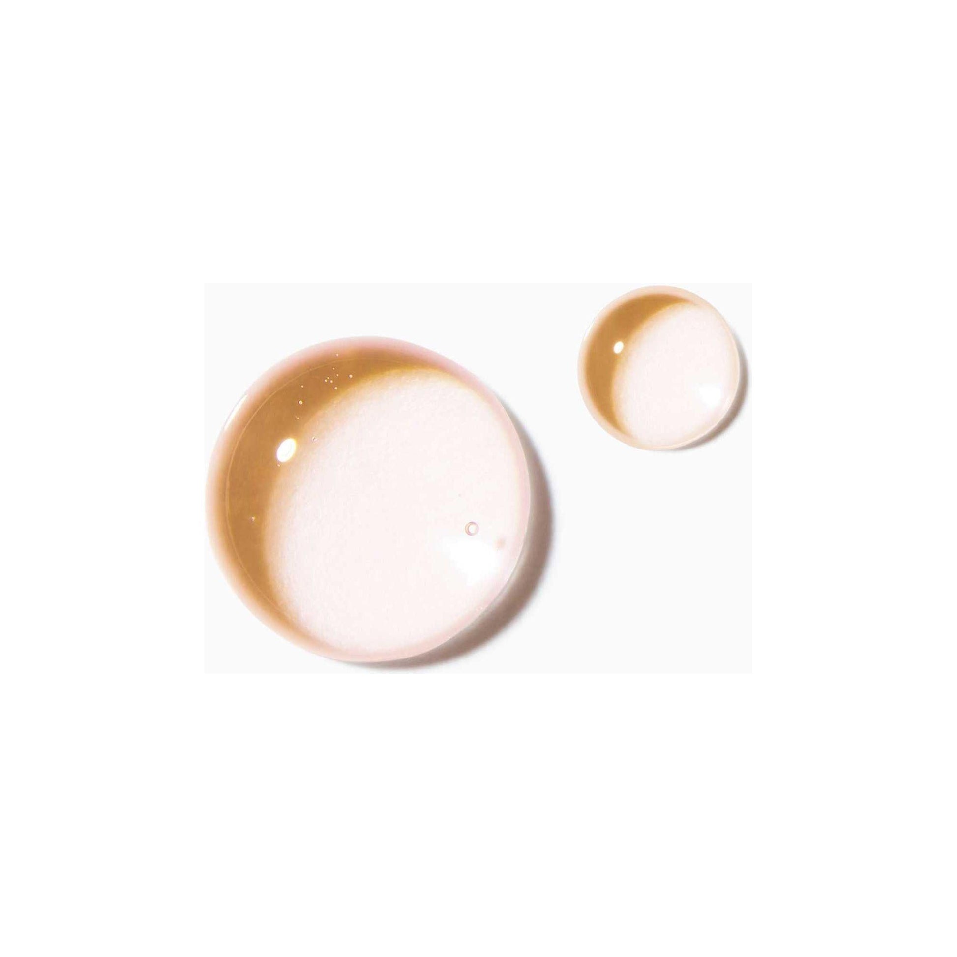 Close-up of two transparent drops of Kérastase Nutri-Supplement Scalp Serum showcasing its non-greasy texture.