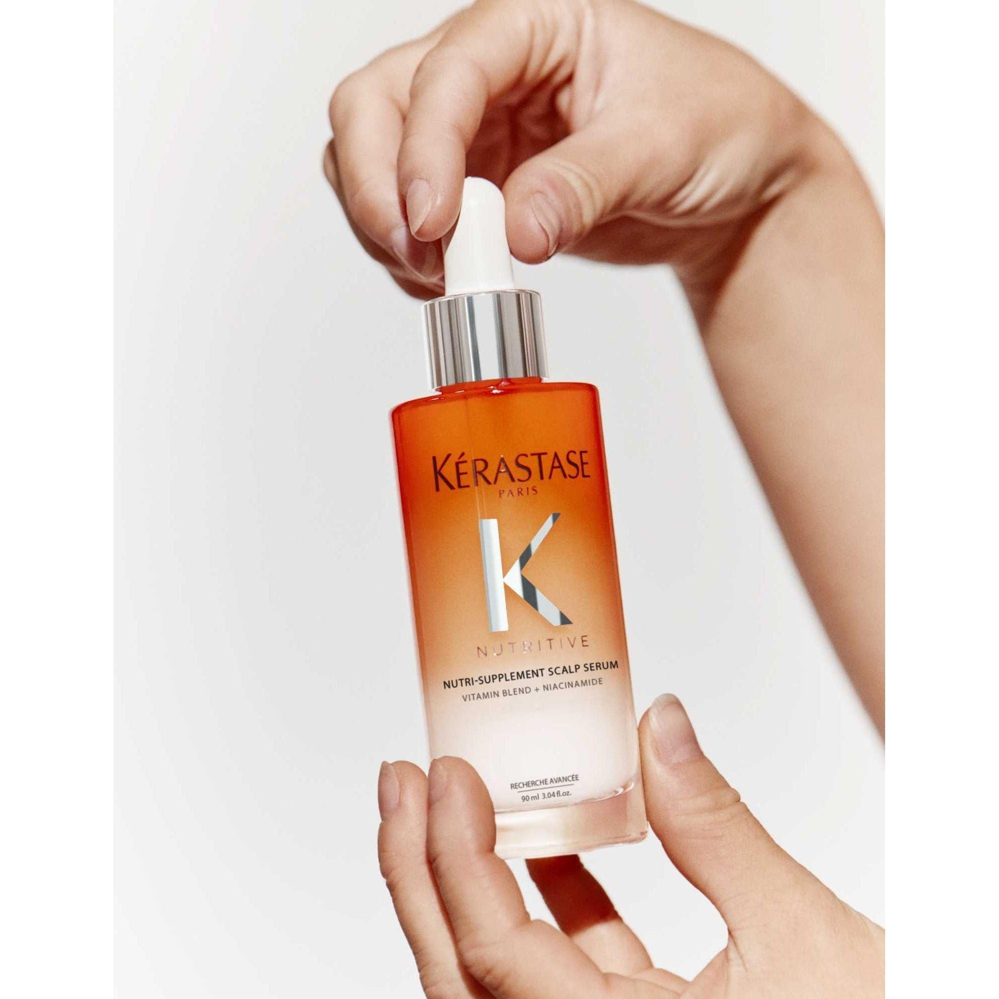 Kérastase Nutri-Supplement Scalp Serum in hands, nourishing dry scalp with vitamins and niacinamide.