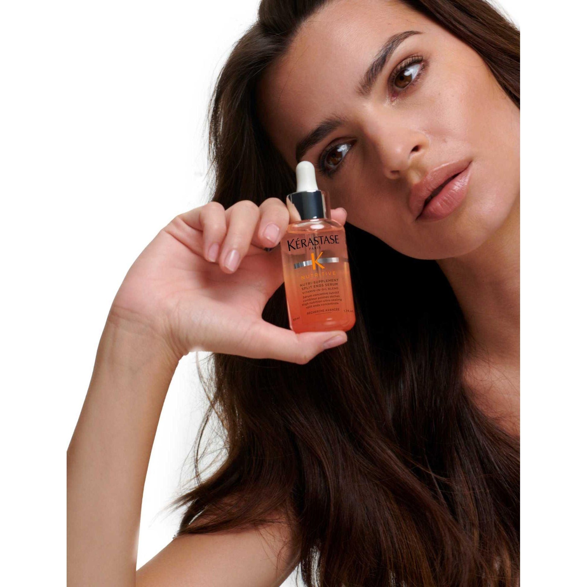 Kérastase Nutri-Supplement Split Ends Serum held by model, showcasing split ends treatment for dry hair.