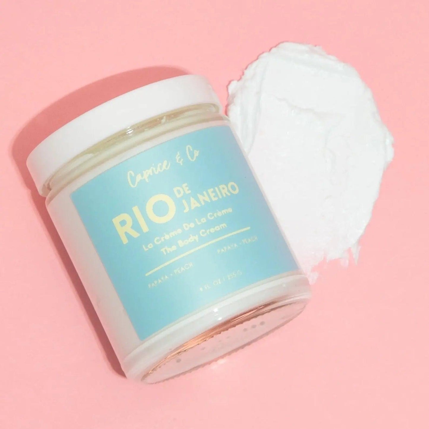 Rio de Janeiro body cream jar and creamy texture on a pink background, featuring natural ingredients for hydration.