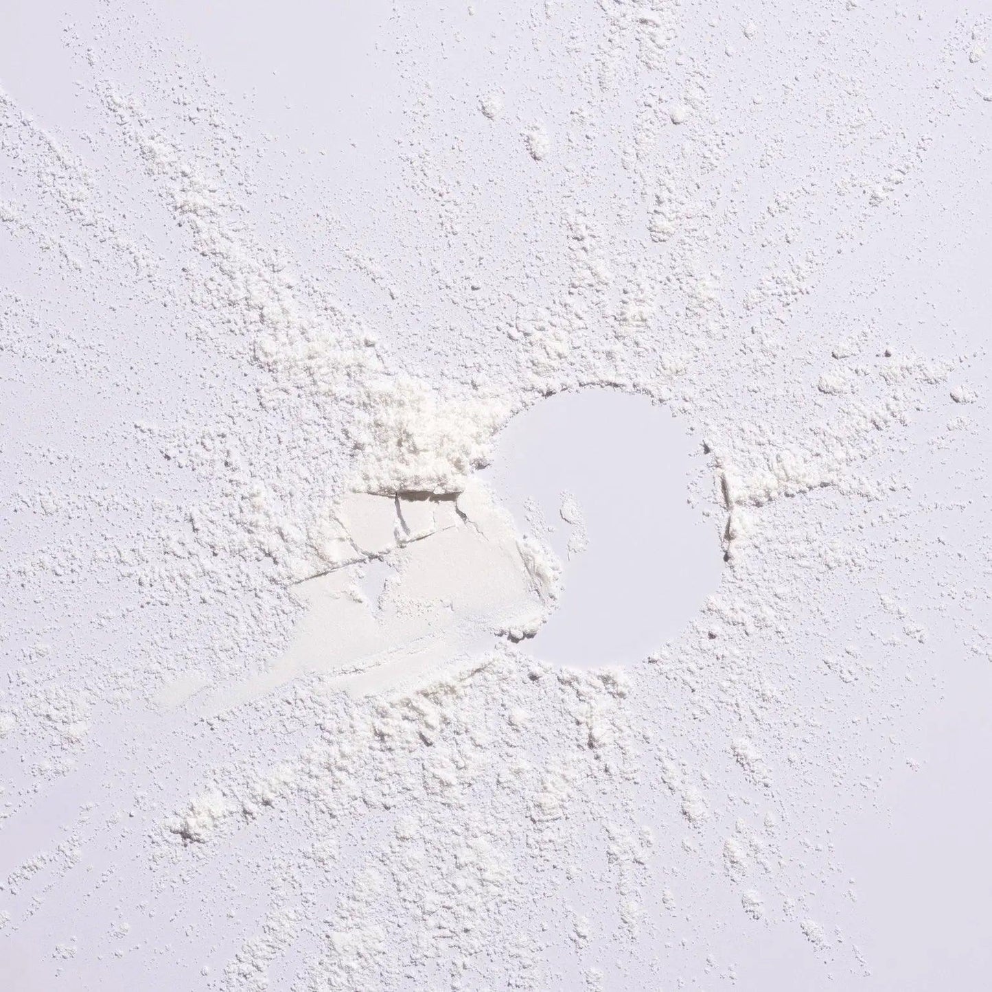 White powder scattered on a surface, representing Serene Scalp Oil Control Dry Shampoo Powder by Shu Uemura.