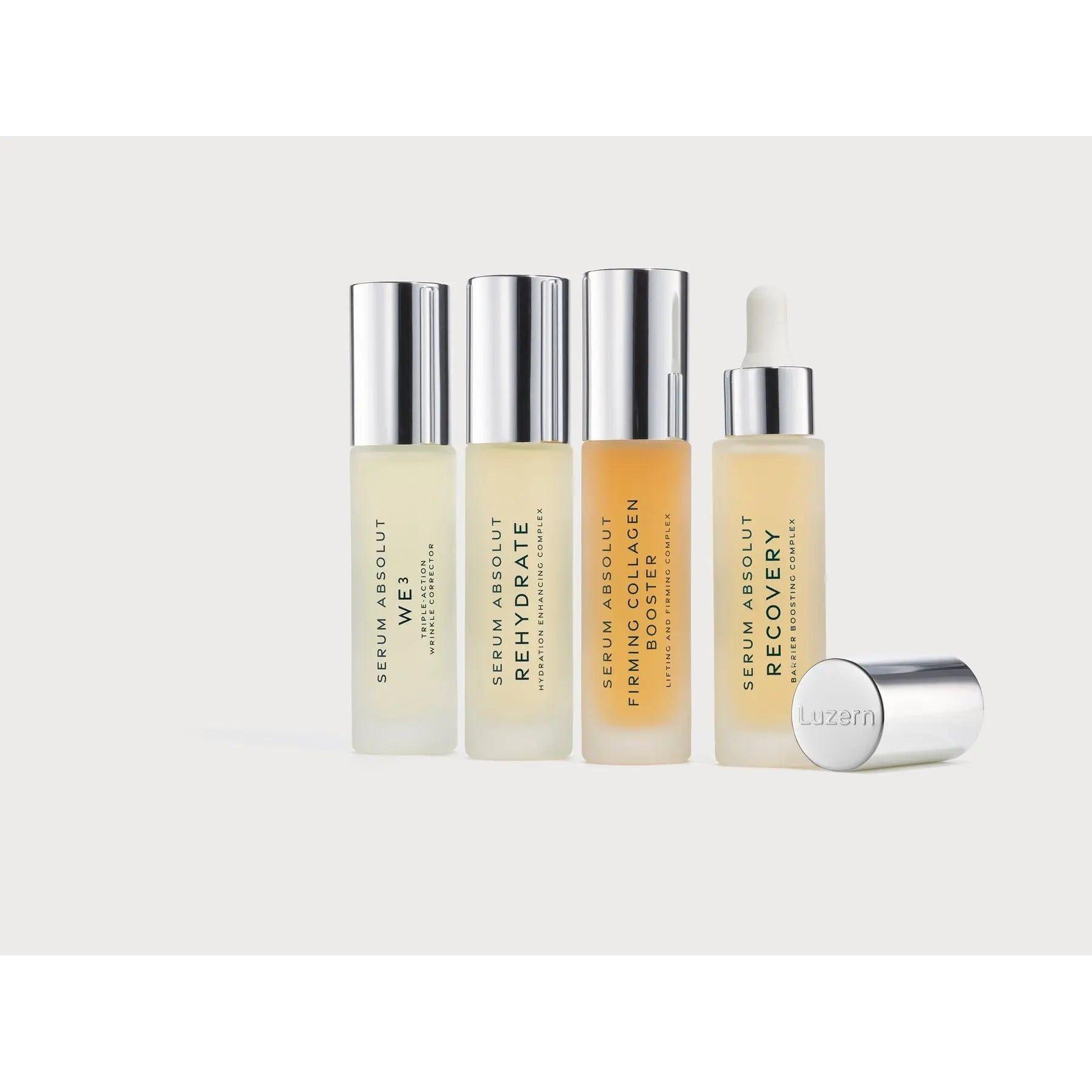 Four bottles of Luzern Serum Absolut skincare products for eyes, rehydration, collagen boost, and recovery, with one bottle cap off.
