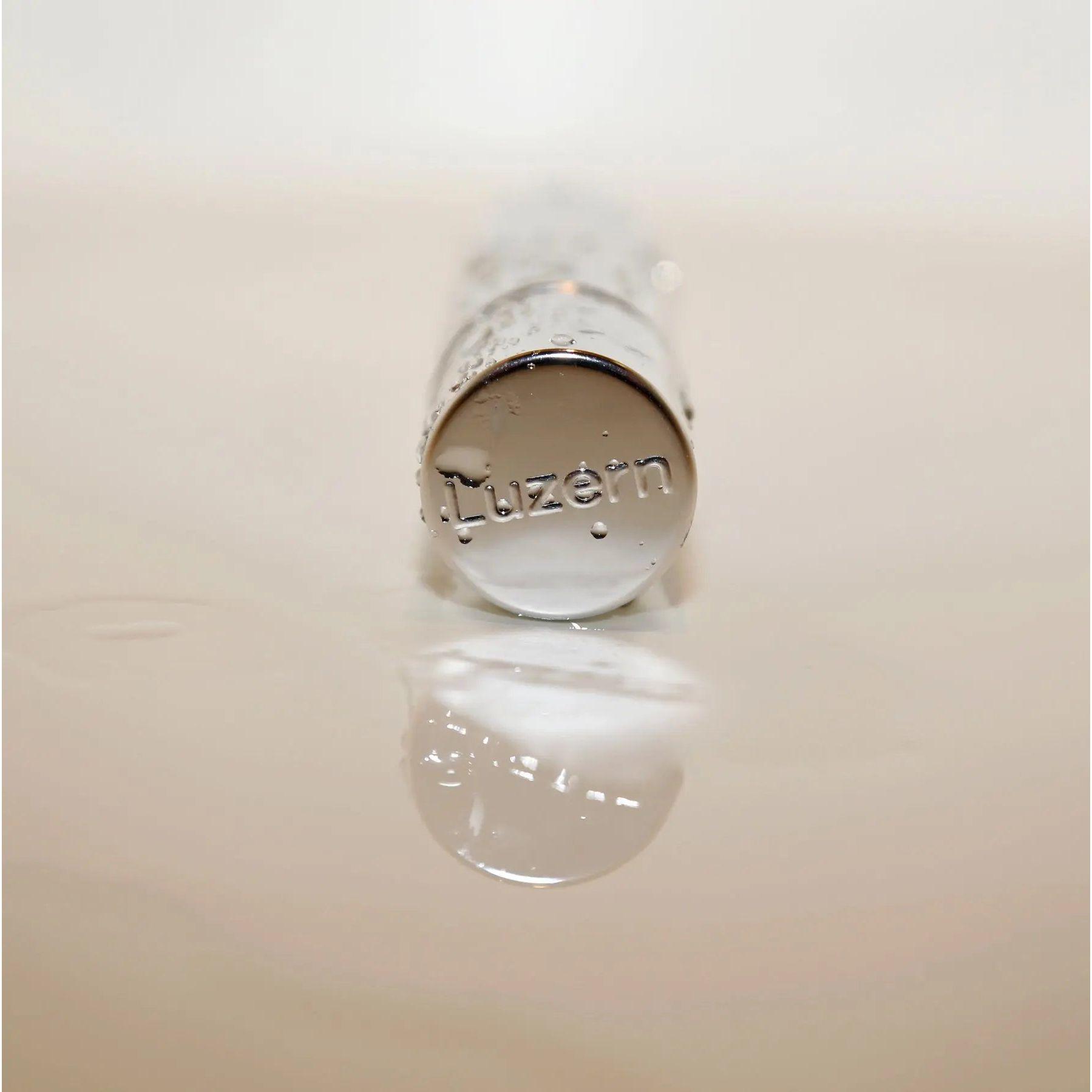Lucerne skincare product bottle reflection on water surface.