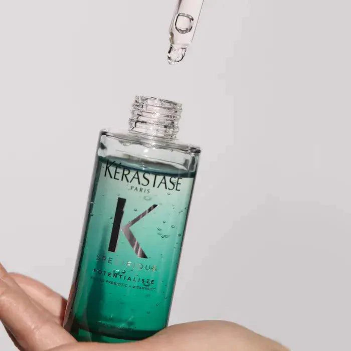 Kérastase Potentialiste Hydrating & Soothing Scalp Serum in a hand, with dropper dispensing the lightweight formula.