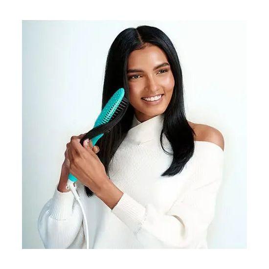 Woman with long hair smiling while using a Smooth Style Ceramic Heated Brush for sleek, beautiful hair.