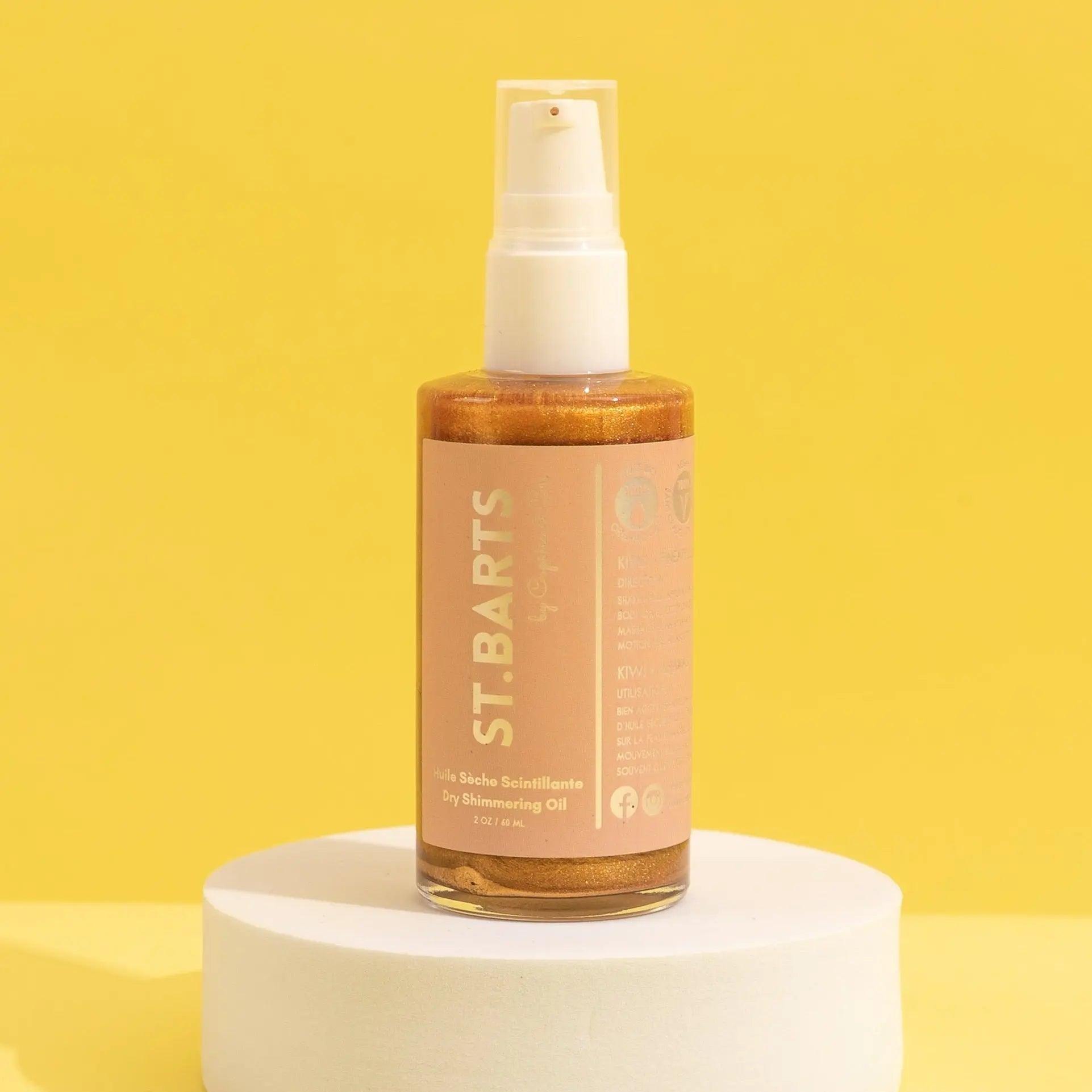 St.Barts Dry Shimmering Oil in a 2 oz bottle, featuring a bronze hue, set against a bright yellow background.
