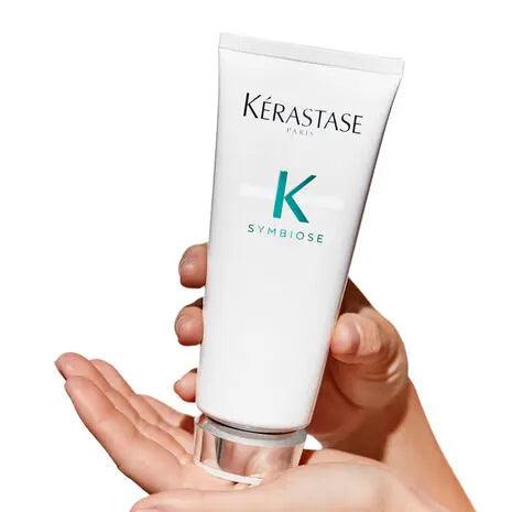 Kerastase Symbiose Fondant Apaisant Essentiel hair conditioner tube held in hand for scalp soothing and hydration.