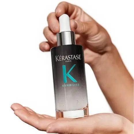 Kérastase Symbiose Sérum Nuit Intensif in hand, designed to rejuvenate and revitalize damaged hair.