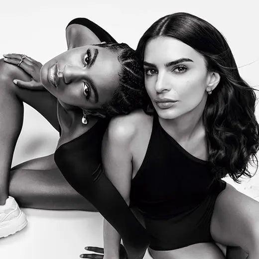 Two women posing confidently in black outfits, showcasing elegance and style in a striking monochrome image.