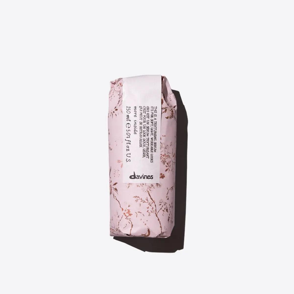 Elegant Davines hair care product in pink floral packaging on white background.