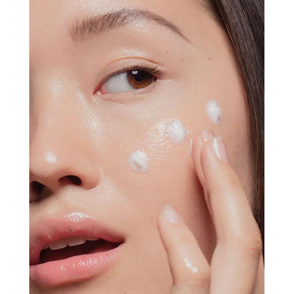 Close-up of a woman's face applying ultra-rich moisturizer for intense hydration and skin suppleness.