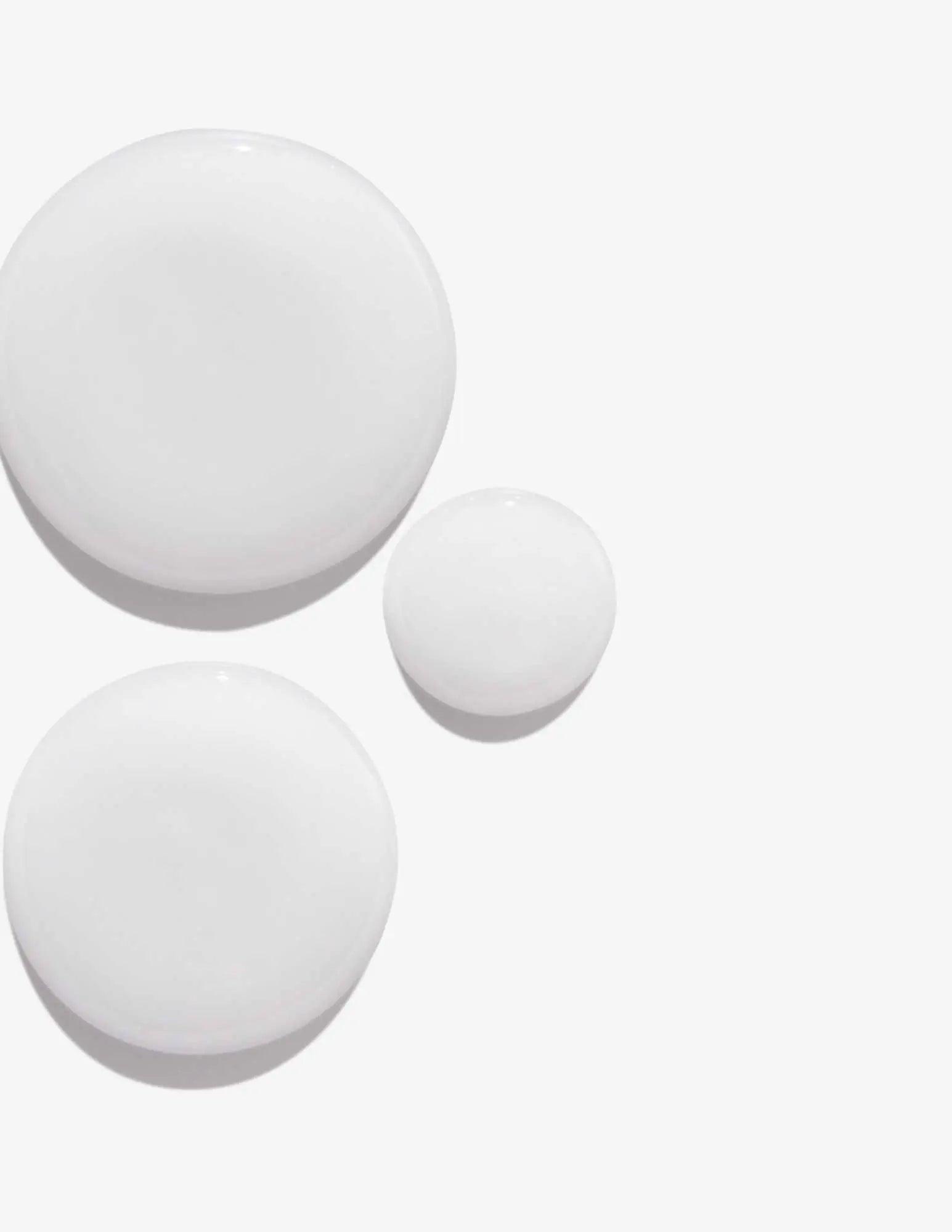 three circular white cosmetic containers on a plain background