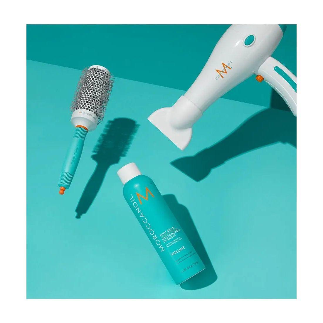 Moroccanoil® Volume Root Boost spray with styling tools on a bright turquoise background for big hair volume.