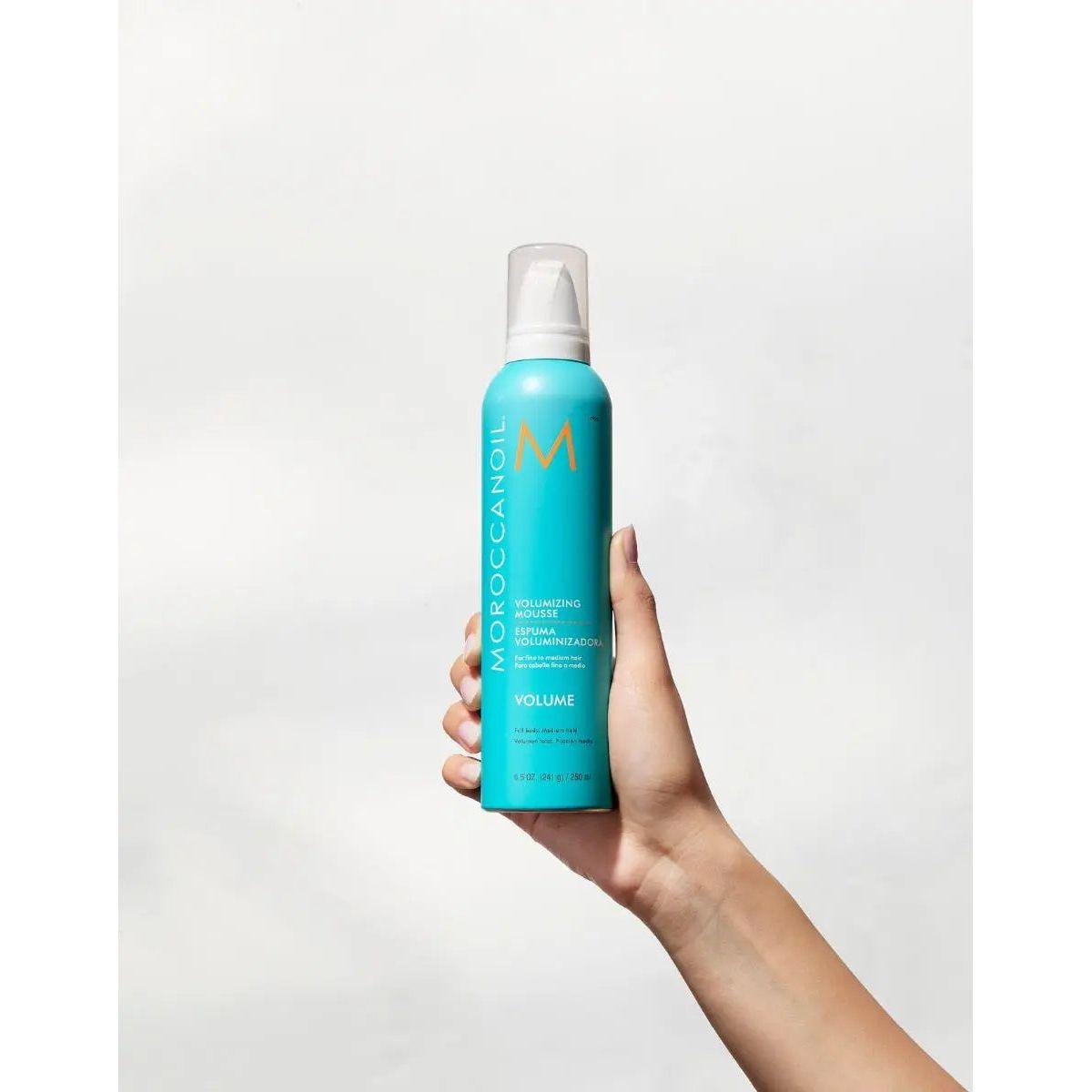 Moroccanoil Volumizing Mousse bottle held in hand, designed for instant volume and lift in fine hair.